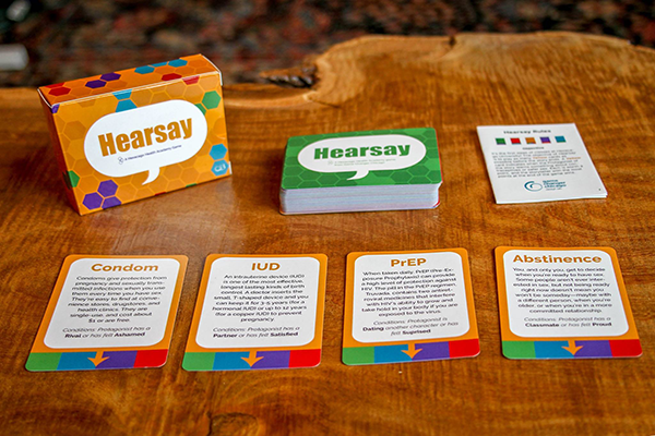 Close-up of the colorful card game Hearsay, with description cards for contraception methods (condoms, IUD, PrEP, abstinence), and other dealt cards that are lined up in a column