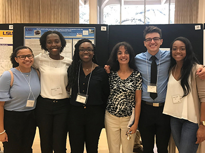 Vicente with five IMSD scholars, standing in front of presentation posters.