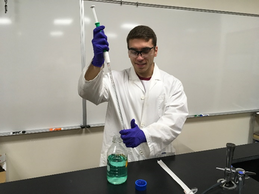 Hunter McCurdy in a lab, using a long syringe to fill a glass vial.