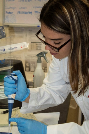 Mariajose Franco in a lab, using a pipette to fill a glass vial.