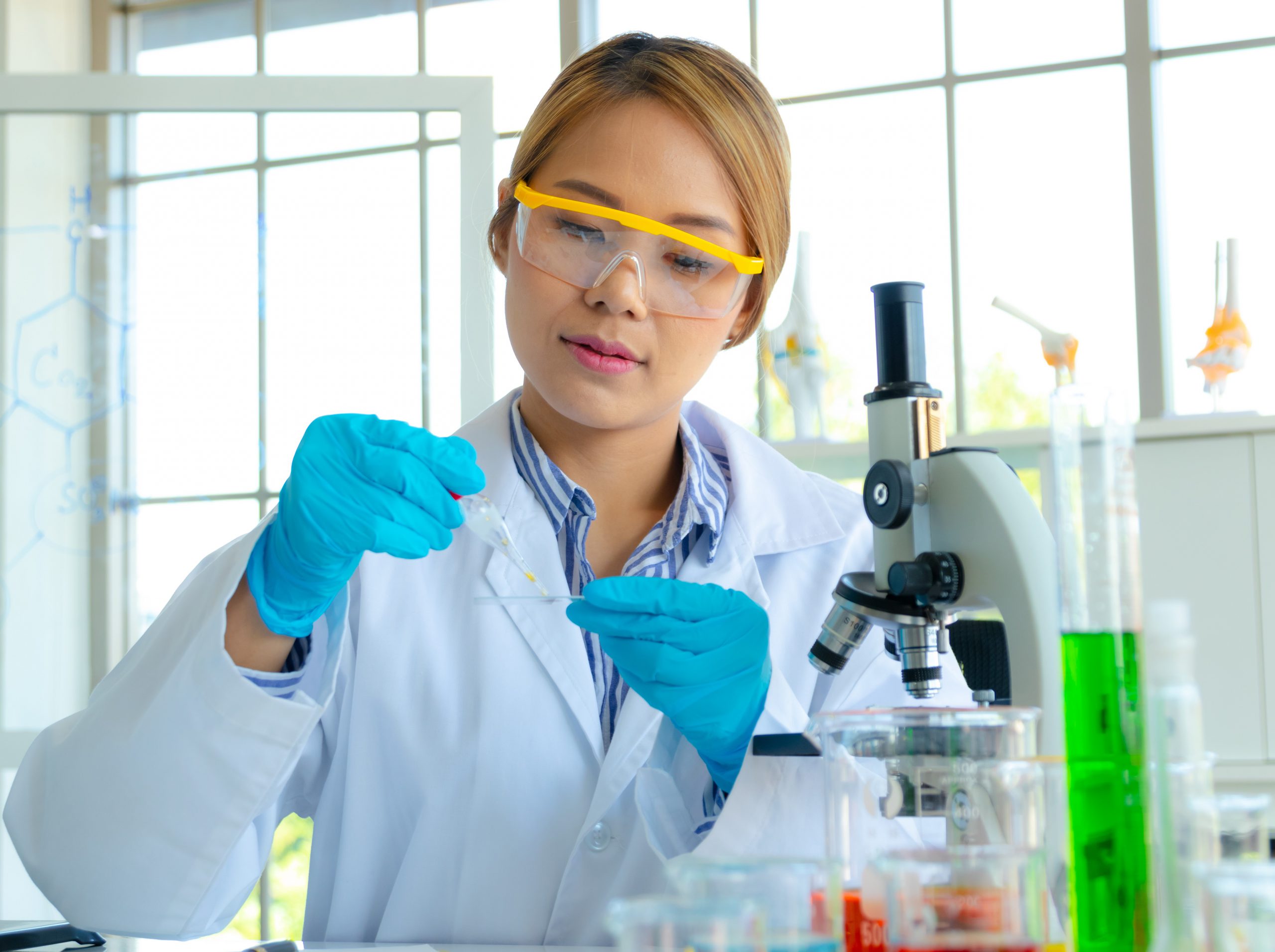 A female scientist in a lab preparing a slide to put under a microscope.
