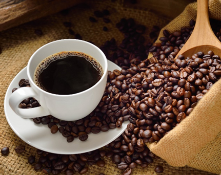 A cup of coffee next to coffee beans on a table.