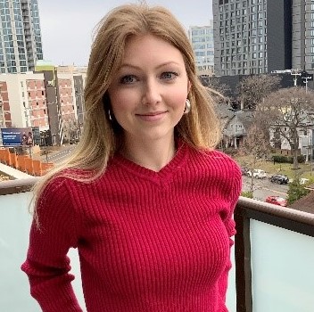 Anna Bright on a balcony overlooking a cityscape.