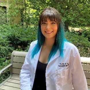 Christina Chavez in a lab coat sitting on a park bench.