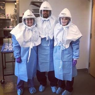 Dr. Ramos-Benítez standing between two other researchers in a lab, all wearing personal protective equipment.