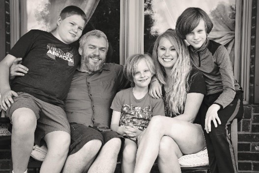 Dr. Bohannon sitting on a bench in front of a window with her husband and three children.