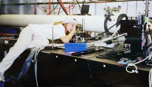 Dr. Jackson looking into an instrument in a lab with other scientific equipment in the background.