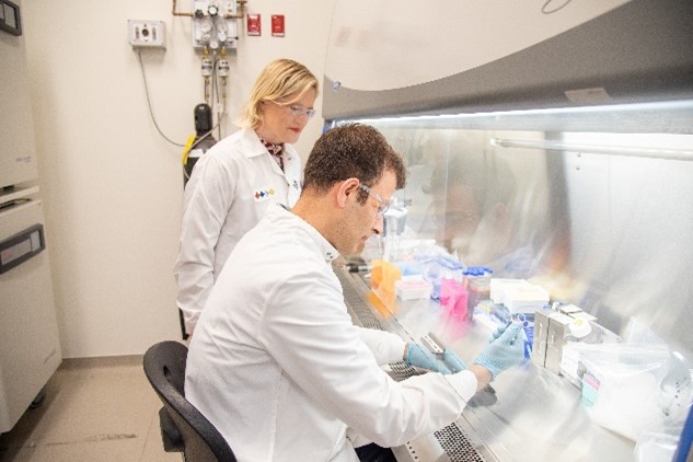 Dr. Jones standing behind a student working in a fume hood.