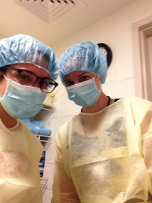 Dr. Boros and another person in a lab, wearing surgical gowns, masks, and hairnets.