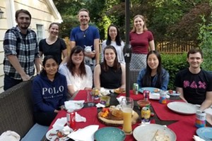 A group of 10 people outdoors around a patio table.