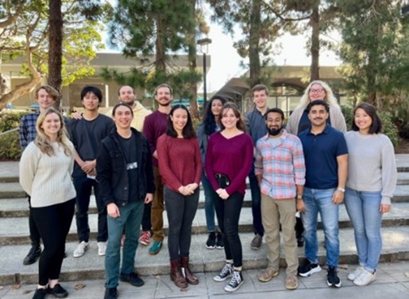 A group of 14 people posing for a photo outdoors.