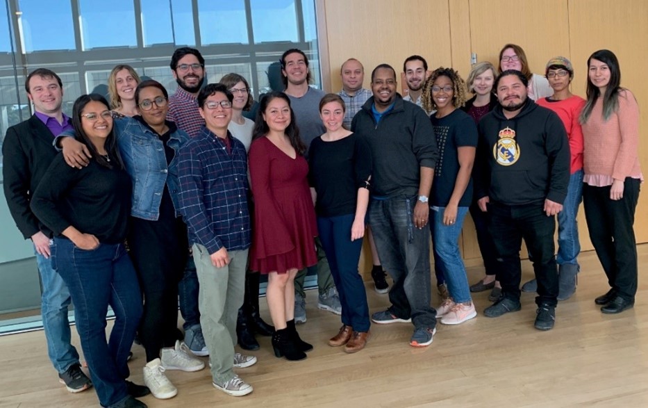 A group of 19 people standing together and smiling.