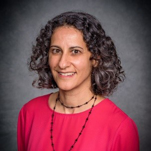 A headshot of Dr. Talene Yacoubian in a red blouse and black-beaded necklace. 