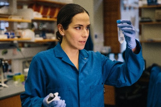 Dr. Landry standing in a lab holding a test tube.