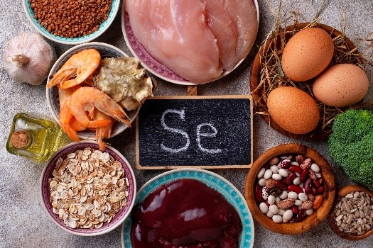 A small chalkboard with selenium’s atomic symbol “Se” written on it, surrounded by foods including shrimp, oats, liver, beans, eggs, and chicken.