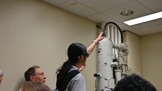A student with their hand outstretched to feel the top of a large, cylindrical machine.