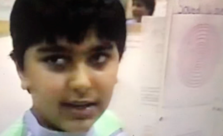 Dr. Garg as a boy speaking to a camera with a poster board about sound waves behind him.