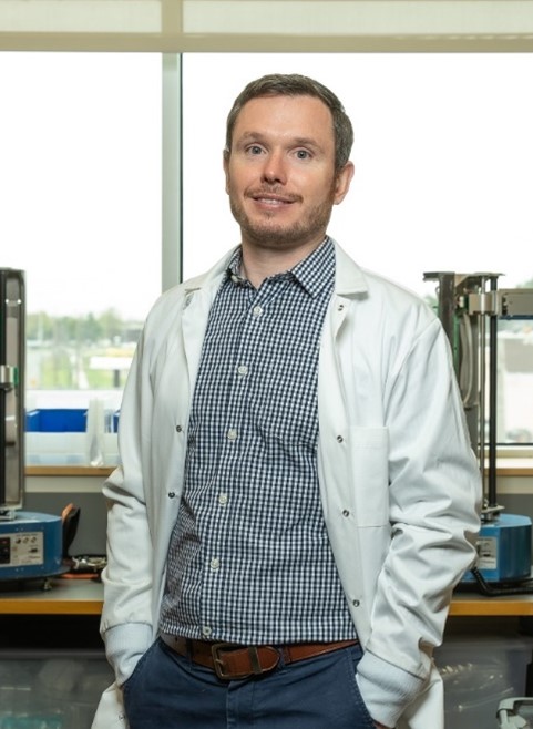 A portrait image of Dr. Gormley, wearing a white lab coat in the laboratory.