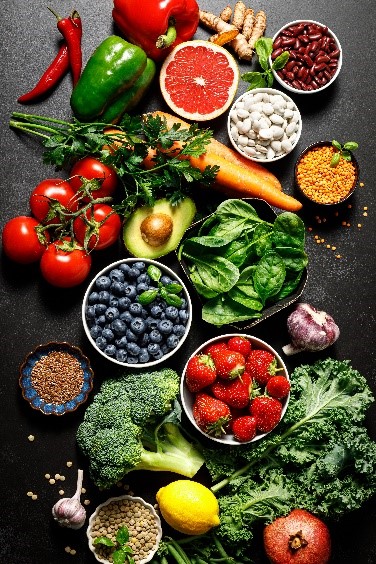 A spread of antioxidant-rich foods such as strawberries, kale, lemon, spinach, blueberries, tomatoes, parsley, grapefruit, carrots, and legumes.