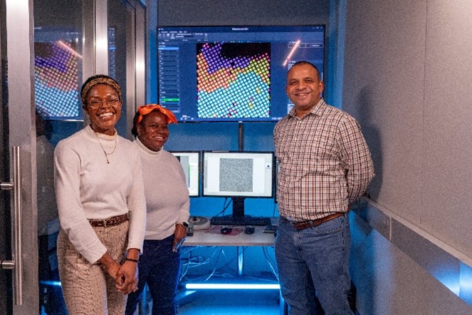 Dr. Jimah with two others standing in front of several computer screens.