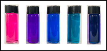 Five vials of brightly colored pink, purple, blue, and green liquids.