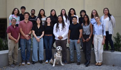 Dr. Bil Clemons surrounded by 17 people and a dog.